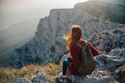 Rear view of woman sitting on rock