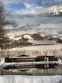 Scenic view of lake by building against sky during winter