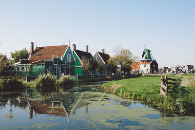 Houses by water against clear sky