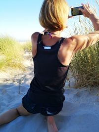 Rear view of woman photographing at beach