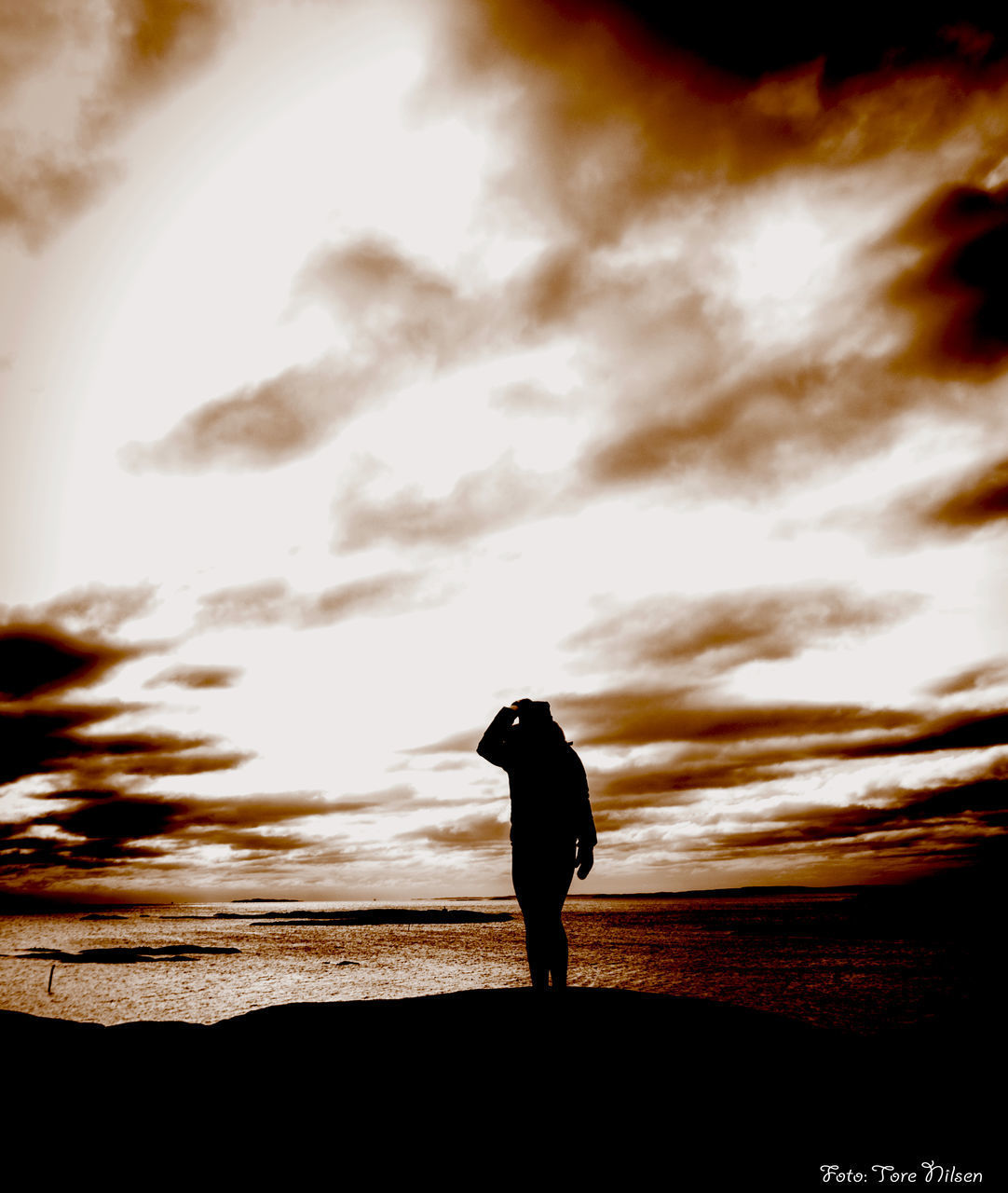 SILHOUETTE MAN STANDING AGAINST SEA DURING SUNSET