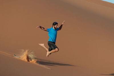 Low angle view of man jumping on sand at sunset