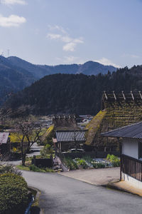 Houses by trees and mountains against sky