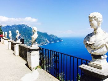 Statue by sea against blue sky