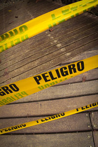 High angle view of yellow cordon tapes over wooden footpath