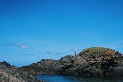 Rock formations by sea against blue sky