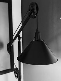 Close-up of electric lamp hanging against wall at home