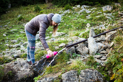 Full length of woman holding umbrella on rock