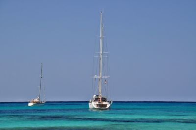 Sailboat sailing on sea against clear sky