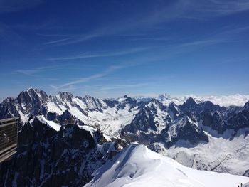 Scenic view of snow covered mountains against blue sky