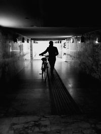 Silhouette man riding bicycle in tunnel