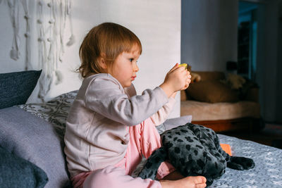 A small child at home on the couch uses a smartphone