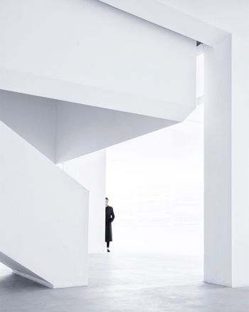 MAN WALKING ON WHITE CORRIDOR