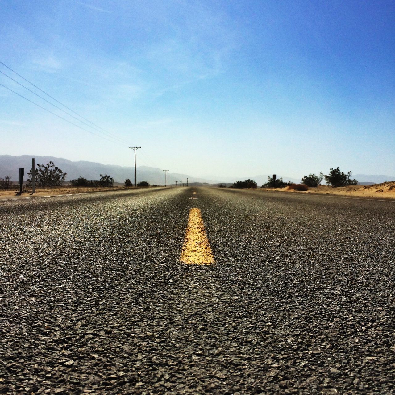 the way forward, diminishing perspective, vanishing point, surface level, transportation, road, blue, asphalt, clear sky, sky, road marking, landscape, long, tranquil scene, tranquility, empty road, empty, copy space, country road, nature
