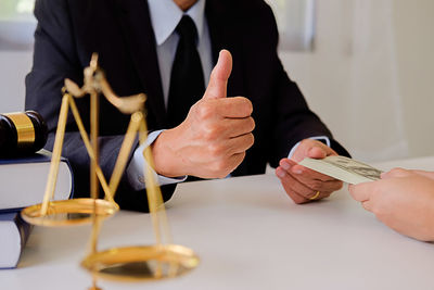 Cropped hands of woman giving bribe to lawyer in office