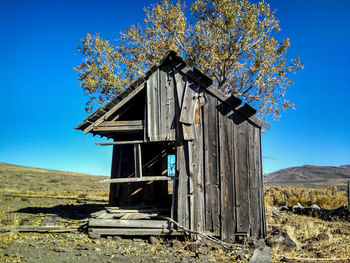 Abandoned built structure on field against clear blue sky