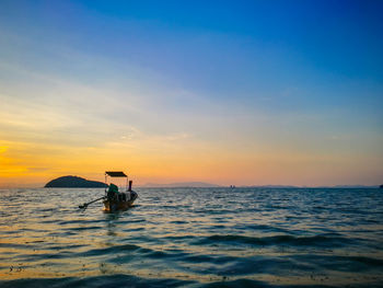 Boat moored in sea against sky during sunset