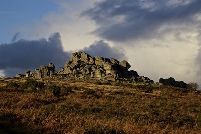Rock formation on hill against sky