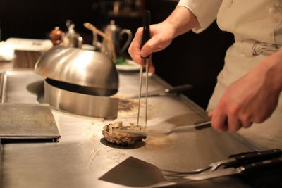 Midsection of chef preparing food in commercial kitchen