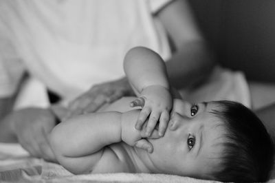 Portrait of cute baby boy lying on bed cared by mother's arms