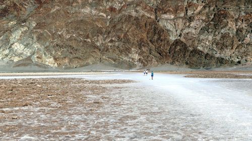 Mid distant view of people at badwater basin against rock formation