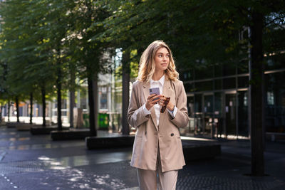 Portrait of smiling young woman standing in city