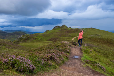 Rear view of woman walking on mountain against sky