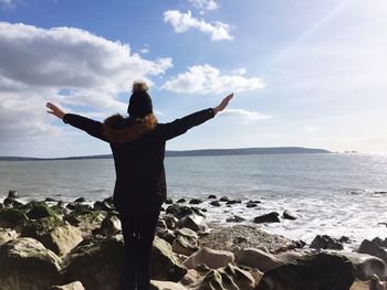 Woman standing at beach against sky