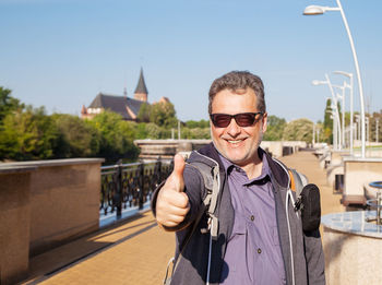 Smiling man on footpath against sky