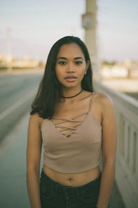 Portrait of young woman standing against blurred background