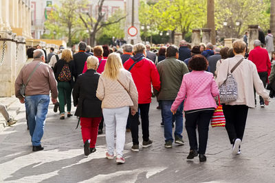 Anonymous people walking  following the tour guide on city street  of sevilla , spain