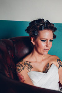 Thoughtful bride sitting on chair at home