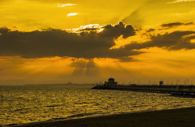 Scenic view of sea against dramatic sky during sunset