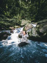 Man standing on rock by river in forest