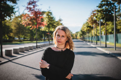 Beautiful young woman standing on road during sunny day