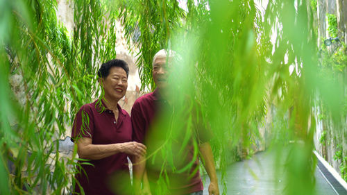 Smiling senior couple standing amidst plants