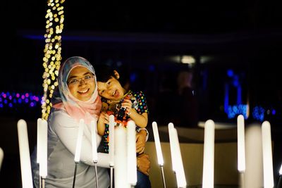 Portrait of mother and son with illuminated lighting equipment at night