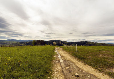 Road amidst field against sky