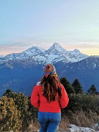 Rear view of woman standing on mountain against sky