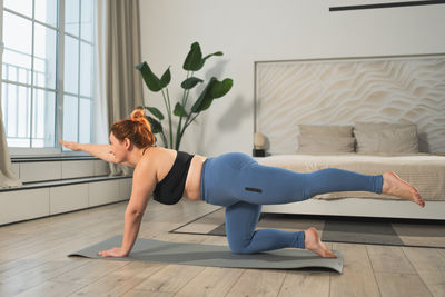 Side view of young woman exercising at home