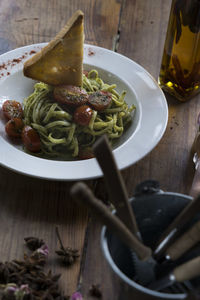 High angle view of bread slice garnished on spaghetti pasta served in bowl on table