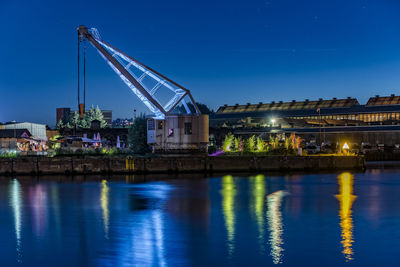Crane by river against sky at night