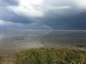 Scenic view of sea against rainbow in sky