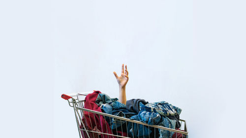 Hand in shopping cart against white background