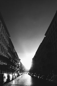 City street amidst buildings against sky at dusk