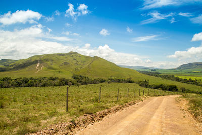 Road amidst field against sky