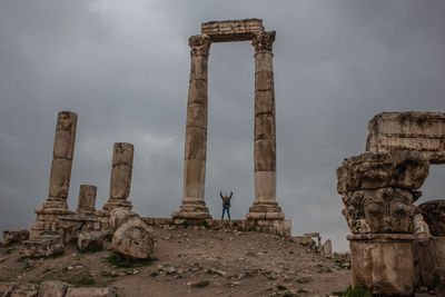 Woman with arms raised standing at temple of hercules