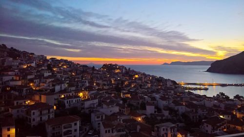 Cityscape by sea against sky during sunset