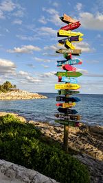 Information sign on beach against sky