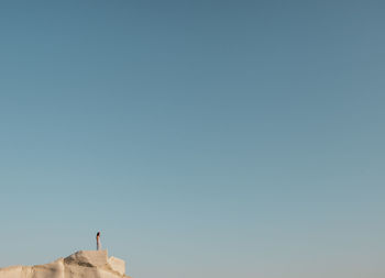 Low angle view of man standing against clear blue sky